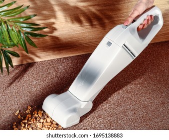 hand of woman with a handy vacuum cleaner picking up cookeie crumbs
