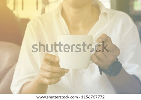 hand of woman hold coffee mug on morning light
