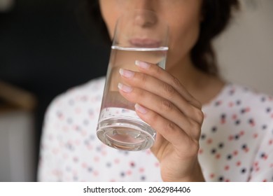 Hand of woman holding glass and drinking fresh pure still cold water, satisfying thirst, keeping detox, healthy hydration and diet, losing weight. Wellness, healthcare, refreshment concept. Close up - Shutterstock ID 2062984406