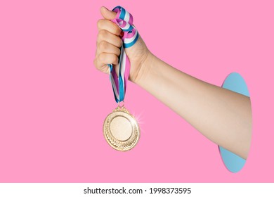 Hand of woman holding gold medal on pink background.award and victory concept.copy space - Powered by Shutterstock