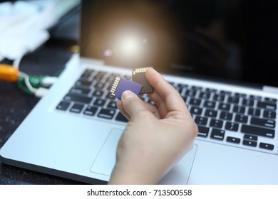 hand woman holding memory card with laptop background. Closeup. - Shutterstock ID 713500558