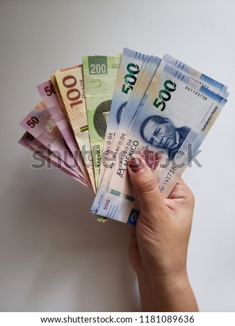 hand of a woman holding mexican banknotes of different denominations