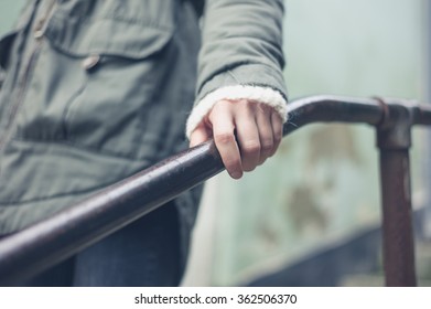 The Hand Of A Woman Holding On To A Metal Banister Outside