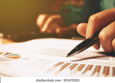 Рука женщина держит ручку указывая на сводную диаграмму отчета и вычислить финансы.