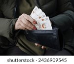 hand of a woman holding sterling bills in her wallet