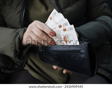 hand of a woman holding sterling bills in her wallet