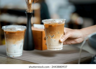 hand of woman holding a take-out iced coffee on black table
 - Powered by Shutterstock