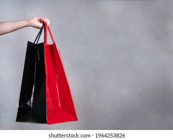 Hand of a woman holds two shopping bags in black and red. On the right is space to put in your own text.