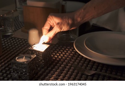 Hand Of Woman Lighting Candles For Popular Shabbat Meal On Friday Night Dinner. Jewish Day Of Rest Tradition