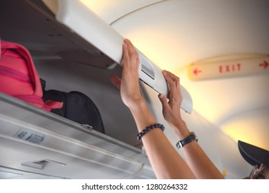 hand of woman passenger of the aircraft holding cover of overhead locker to keep in closed condition, to keep luggages in saft during the flight