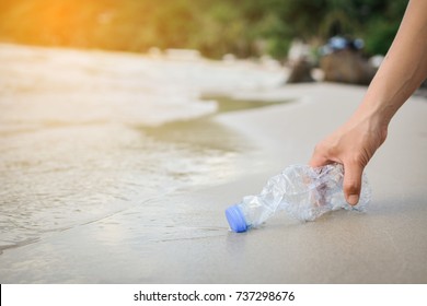 Handfrau, die Plastikflaschenreinigung am Strand abholt , Freiwilligenkonzept