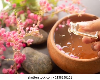 Hand woman pour coconut oil in to aroma essential smell rose flowers with zen pebbles.massage oil.Aroma therapy spa set for luxury bathroom hotel or professional massage aromatic oriental for health.