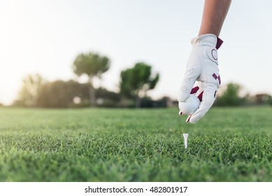 Hand woman putting a golf ball on the tee. Golf Concept. - Powered by Shutterstock