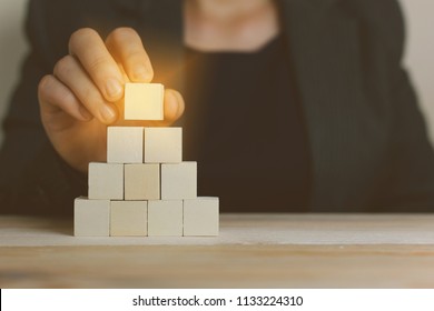 Hand woman putting wood cube block on top pyramid,Human resources, social networking, assessment center concept, personal audit or CRM concept - recruiter complete 