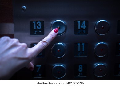 The Hand Of A Woman With Red Fingernails Presses The Number 13 On The Elevator. Many Elevators Leave This Number Out Due To Beliefs That It Is Unlucky.