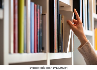 hand of woman searching for a book on shelf - Shutterstock ID 1913208364