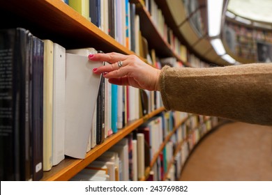 Hand Of Woman Selecting A Book From Book Shelf