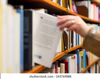 Hand of woman selecting a book from book shelf, blurred motion