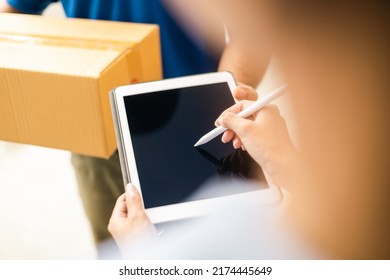 Hand woman signing electronic Signature on tablet for agreement of contract digital receiving parcel from blue delivery man from shopping online. Courier man delivering package to destination. - Shutterstock ID 2174445649