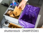 Hand of woman throwing trash into household bins for waste sorting in the kitchen for recycle. Plastic, paper, bio and mixed waste. Sorting waste at home concept. High quality photo