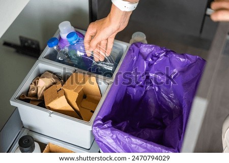 Hand of woman throwing trash into household bins for waste sorting in the kitchen for recycle. Plastic, paper, bio and mixed waste. Sorting waste at home concept. High quality photo