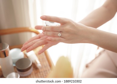 Hand der Frau, die im Wohnzimmer einen Cremelotion-Glas verwendet.