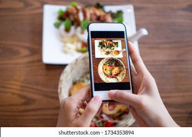 The Hand Of A Woman Using A Mobile Phone To Take Pictures Of Food On The Table To Review And Upload To Social Networks