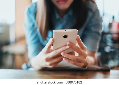 Hand of woman using smartphone on wooden table,Space for text or design.