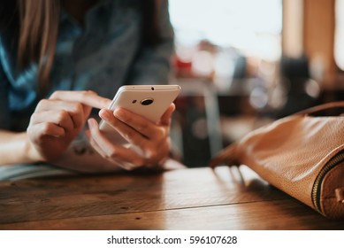 Hand Of Woman Using Smartphone On Wooden Table,Space For Text Or Design.