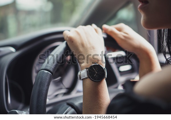 Hand of woman\
wearing watch holding car\
steer