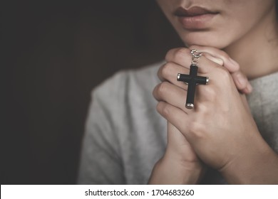 Hand of woman while praying for christian religion, Casual woman praying with a cross, Religion concept.