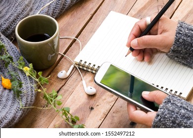 hand of woman writing notebook and mobile phone for business work with hot tea ,knitting wool scarf of lifestyle in winter season decoration on table  - Powered by Shutterstock