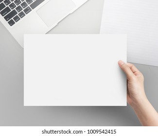 Hand Women Holding Blank Paper A4 Size On Office Table Top View.