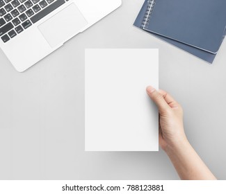 Hand Women Holding Blank Paper A5 Size On Office Table Top View.
