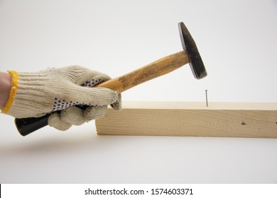 Hand in work gloves hammering nail in a wooden brick
