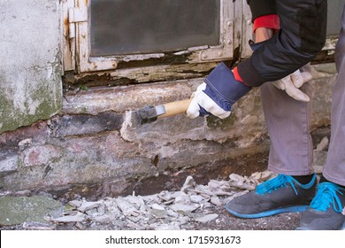 Hand der Arbeiter mit Handschuhen, die Gips auf der Fassade, die zerfällt durch Feuchtigkeit und Schimmel unter einem weißen Holzrahmen aus einem alten Fenster mit Schälen Farbe und verdorbenem Holz. Bild in Nahaufnahme.