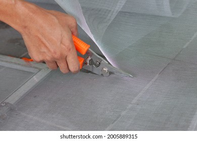 Hand Of Worker Holding Scissors To Cut Mosquito Net Wire Mesh Screen This Is To Be Attached To The Window Of The House To Prevent Insects.