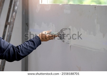hand of worker using gypsum plaster ceiling joints at construction site