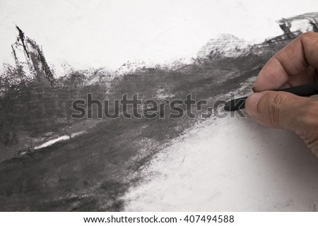 A hand working on charcoal drawing