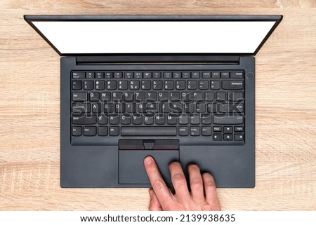 Hand working on a computer touchpad. A man is working by using a laptop computer on  wooden table.  Top view, business office workplace