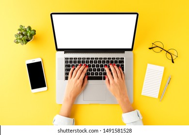 Woman’s hand working on laptop with empty screen. Business background with mobile phone, notebook, pen and eyeglasses. Top view - Powered by Shutterstock