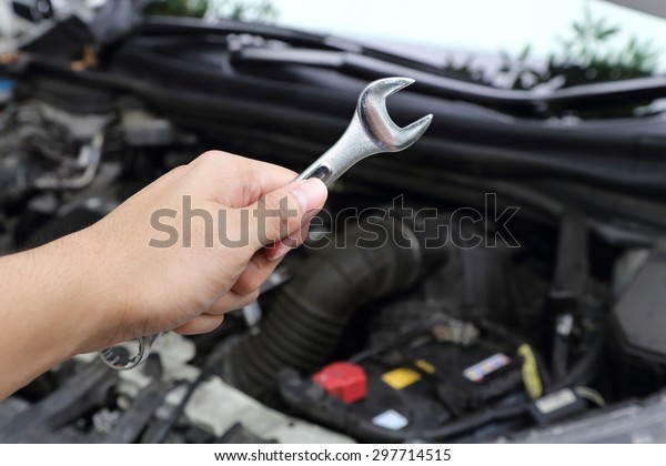 hand with wrench on\
car engine background
