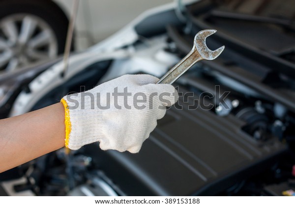 Hand with\
wrench repairing and checking car\
engine