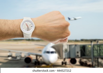 hand with wristwatch with airport in the background as the concept of punctuality in the transport