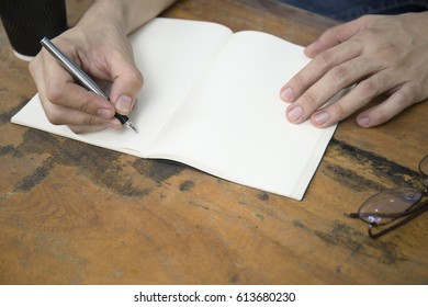 Hand Writes A Black Pen In A Notbook With Cup Of Coffee And A White Telephone