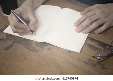 Hand Writes A Black Pen In A Notbook With Cup Of Coffee And A White Telephone