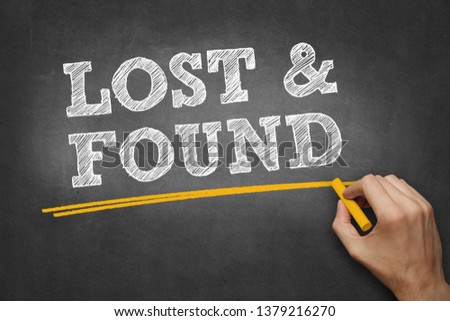 hand writes chalk text on blackboard - LOST and FOUND