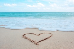 Die Hand, Die Ein Herz Schreibt, Das Am Strand Durch Das Meer Mit Weißen Wellen Und Blauem Hintergrund Geformt Ist