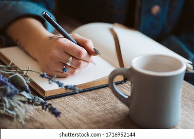 Hand writing in journal with coffee mug