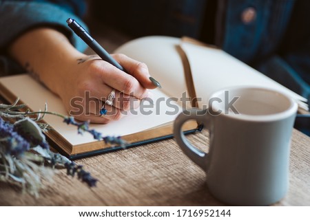 Hand writing in journal with coffee mug